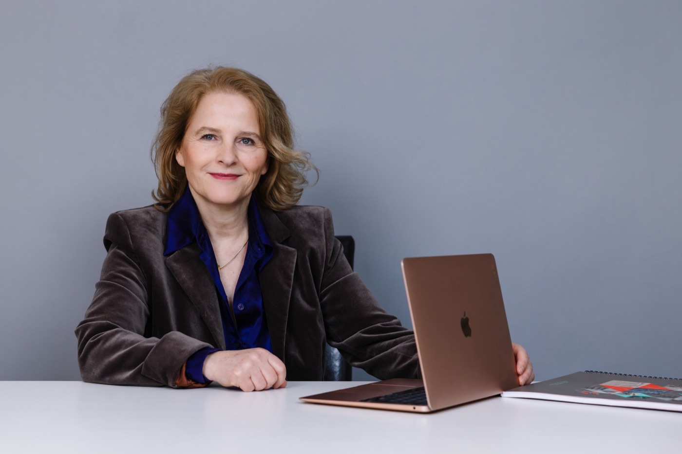 Evamaria Wagner sitzt lächelnd an einem Schreibtisch mit Laptop